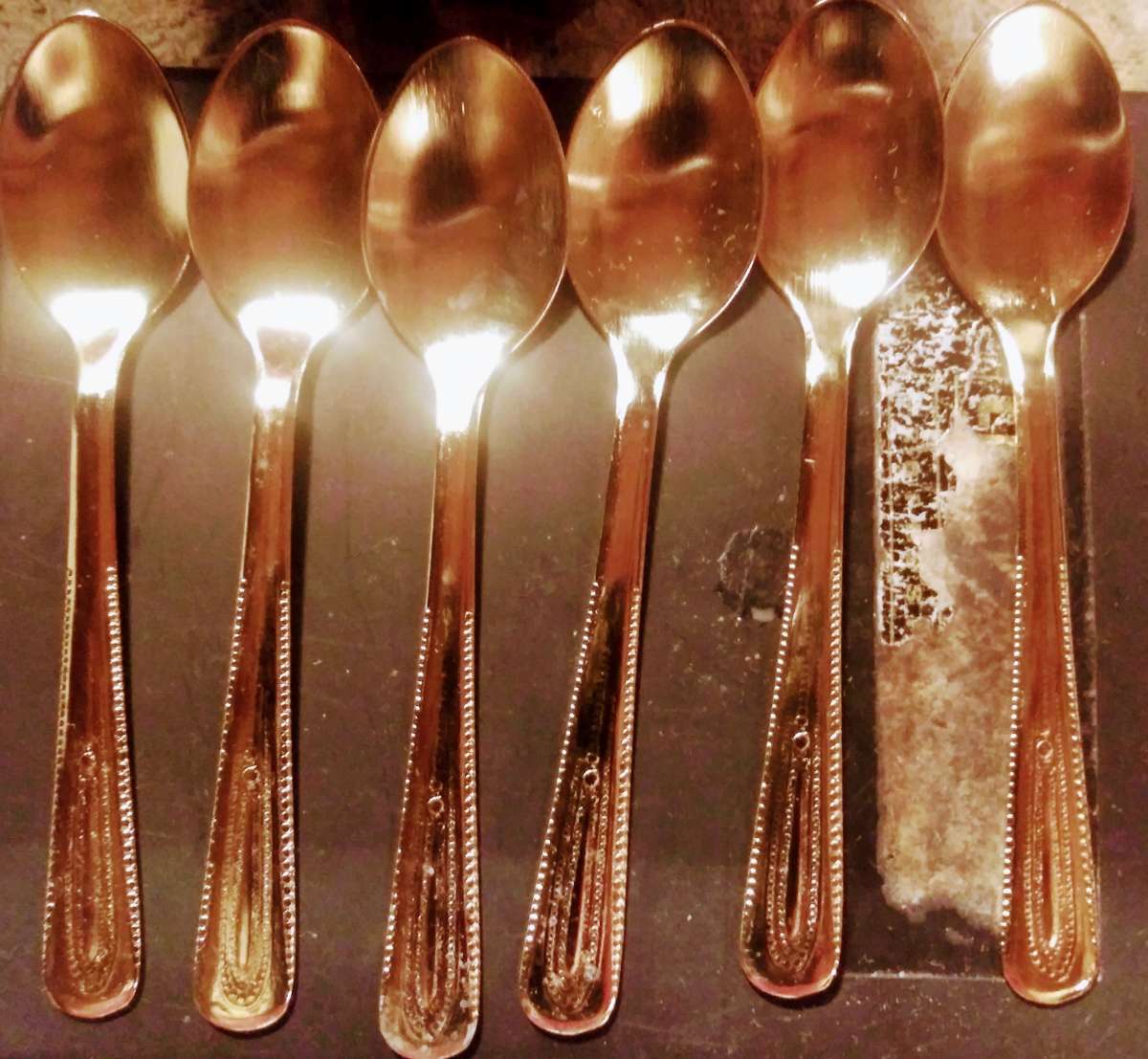 Set of six tiny stainless steel spoons finished in gold