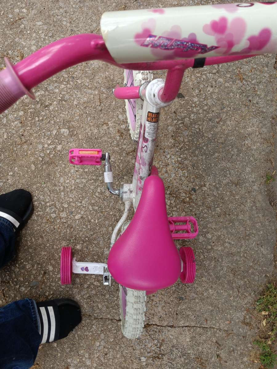 a healthy Barbie pink and white bike with training wheels
