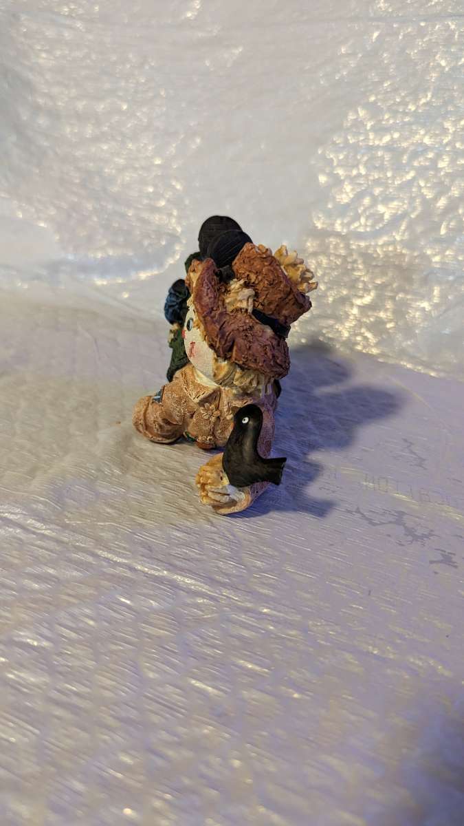 Resin Scarecrow Laying Down With Legs Bent Holding A Crow