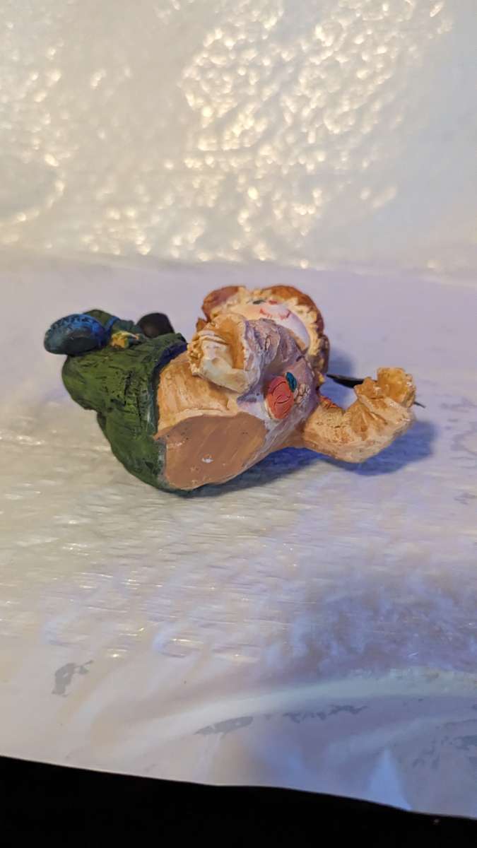 Resin Scarecrow Laying Down With Legs Bent Holding A Crow