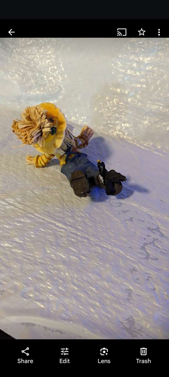 Resin Playful Scarecrow Laying On His Stomach With A Black C