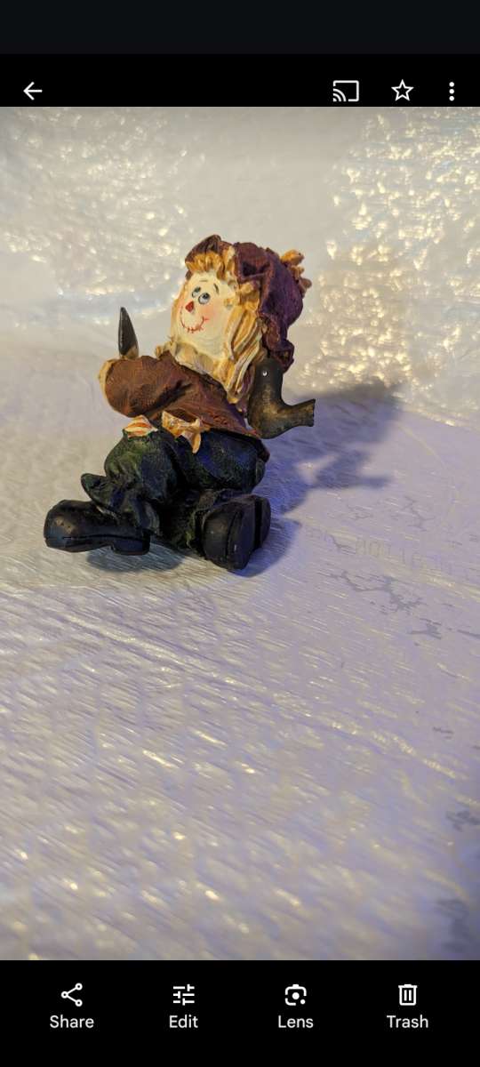 Resin Playful Scarecrow Laying On His Stomach With A Black C