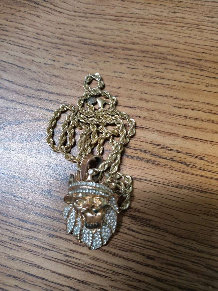 This is a goldtoned lion head pendant with a crown