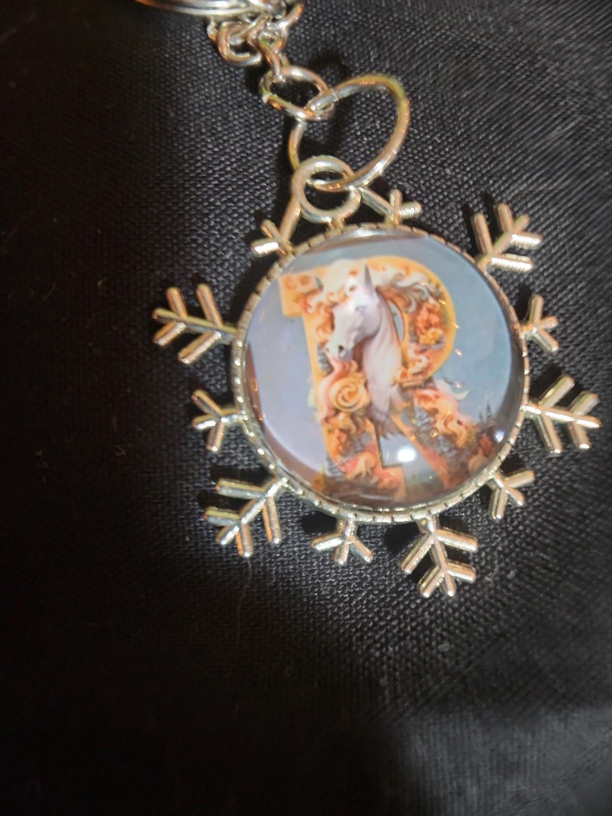 a snowflake pendant with a unicorn and the letter R