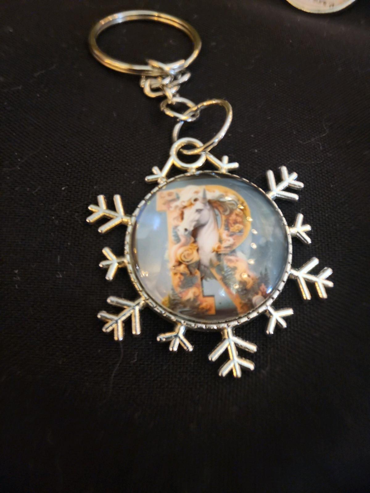a snowflake pendant with a unicorn and the letter R