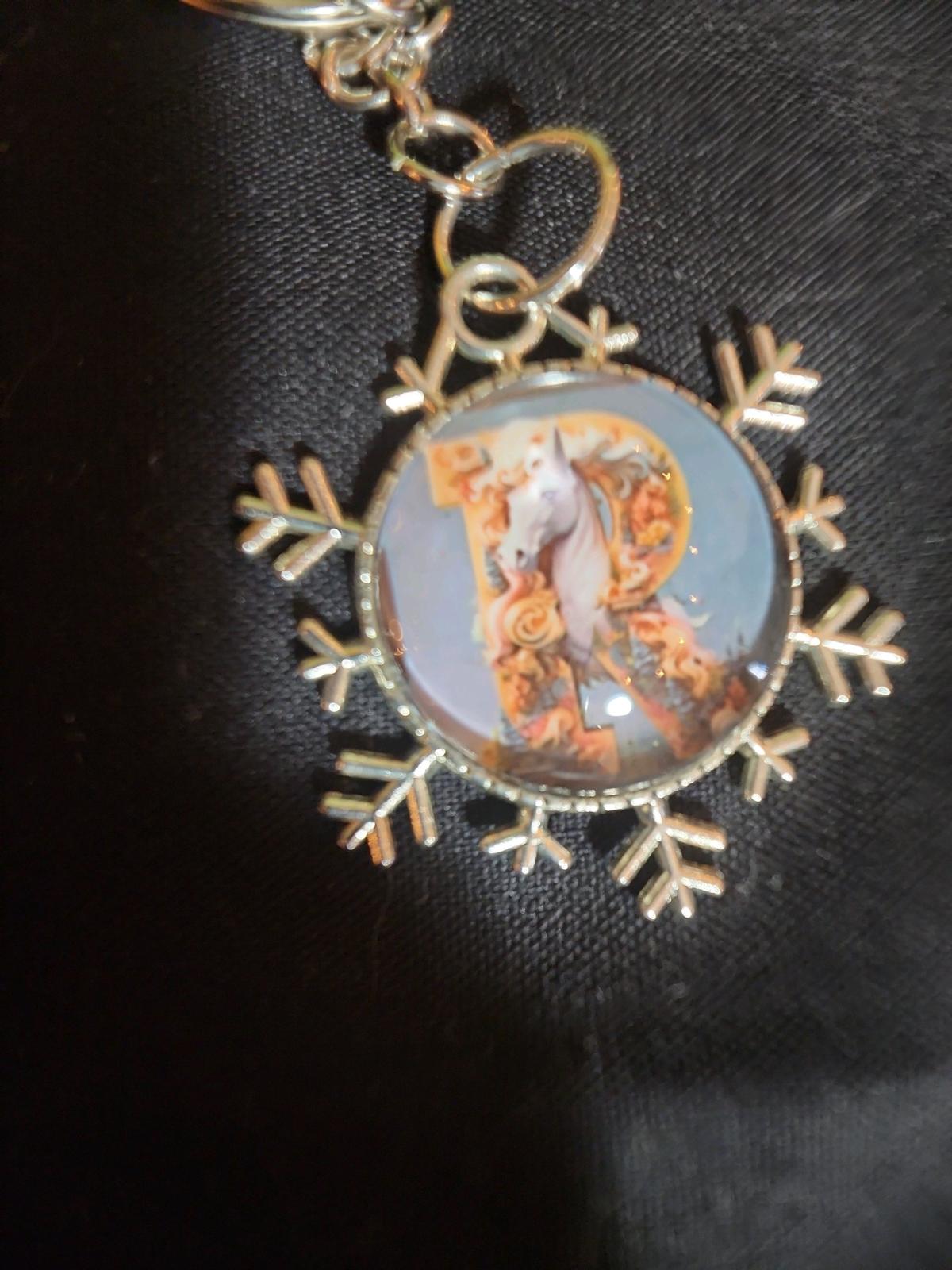a snowflake pendant with a unicorn and the letter R