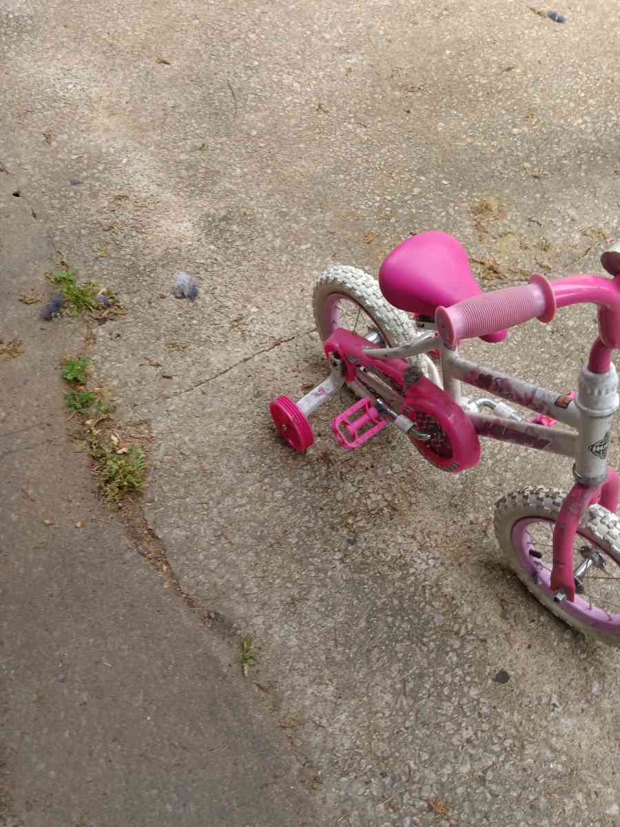 a healthy Barbie pink and white bike with training wheels