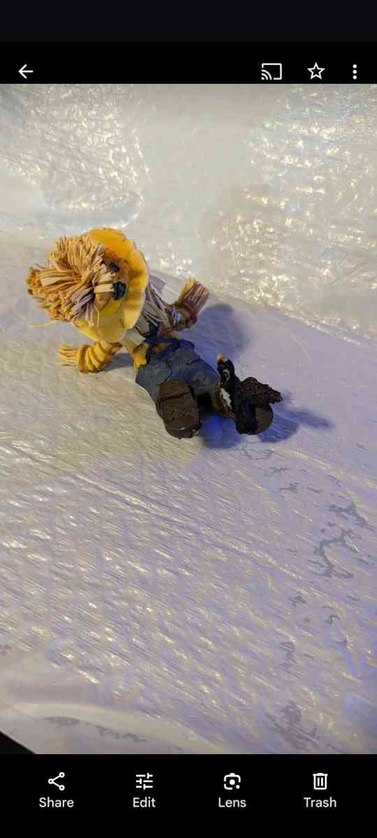 Resin Playful Scarecrow Laying On His Stomach With A Black C