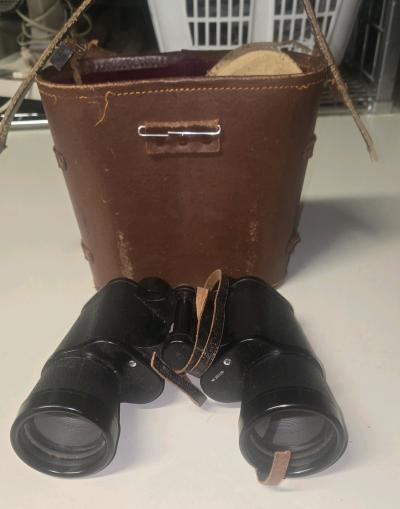 The image shows a pair of vintage black field binoculars wit